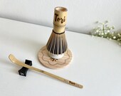 Personalized matcha tea set featuring engraved bamboo whisk and scoop with rhinestones, ceramic black whisk holder, scoop rest, and double-sided engraved wooden coaster. One side of the coaster shows Japanese matcha characters, the other features mat thumbnail 7