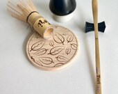 Personalized matcha tea set featuring engraved bamboo whisk and scoop with rhinestones, ceramic black whisk holder, scoop rest, and double-sided engraved wooden coaster. One side of the coaster shows Japanese matcha characters, the other features mat thumbnail 3